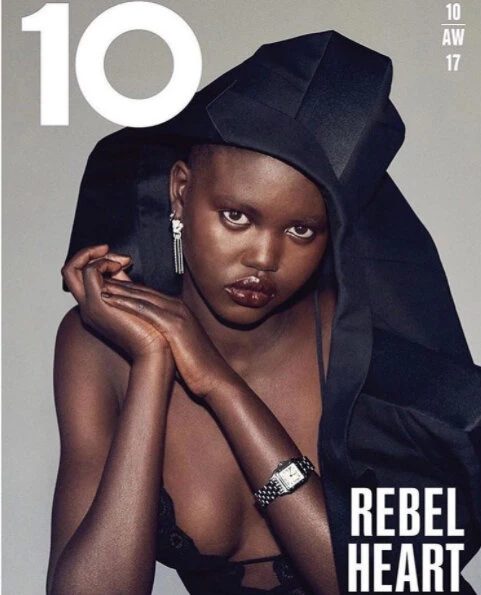 Magazine cover featuring a Black female model wearing a black head covering, earrings, and a watch against a grey backdrop.